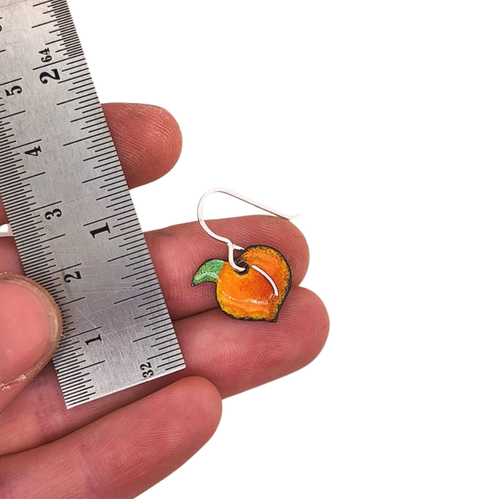 peach earrings next to ruler for scale
