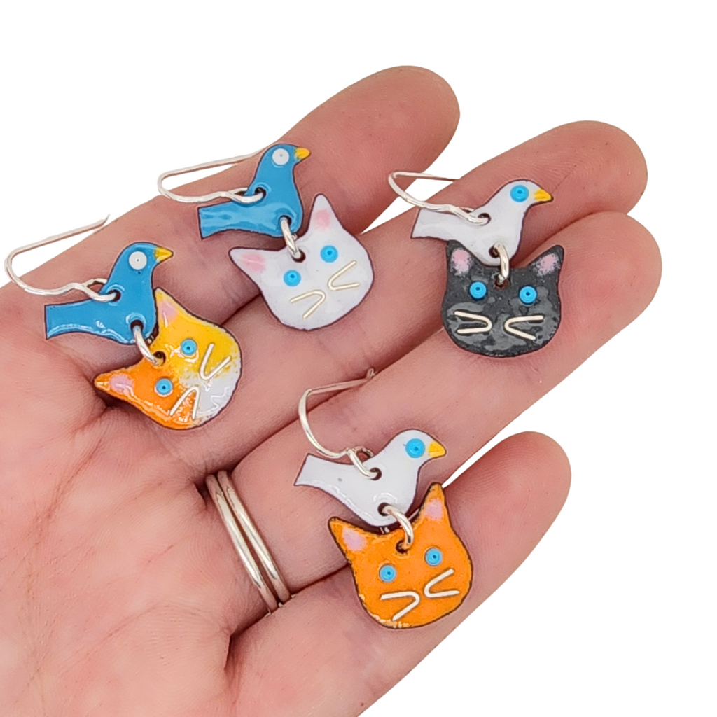 a handful of cat earrings in a variety of color options