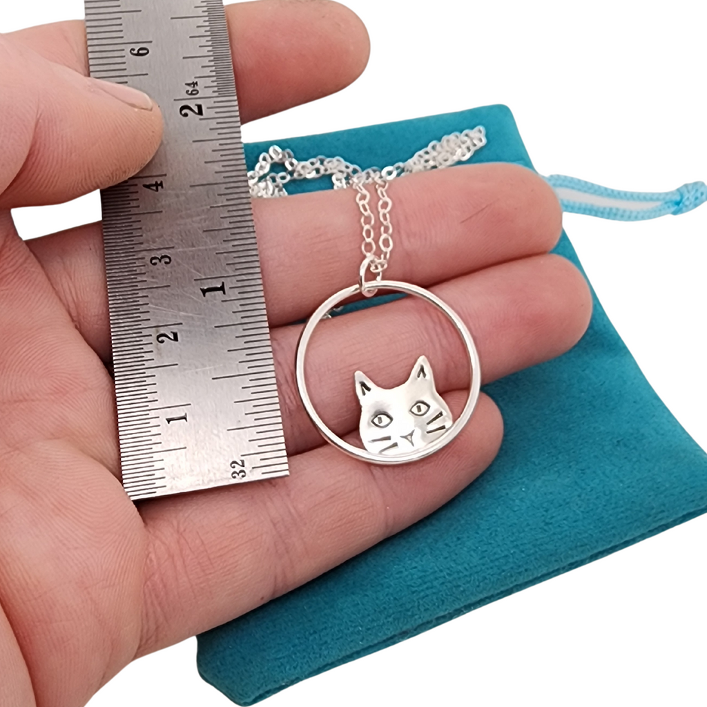 minimalist cat pendant next to ruler for scale