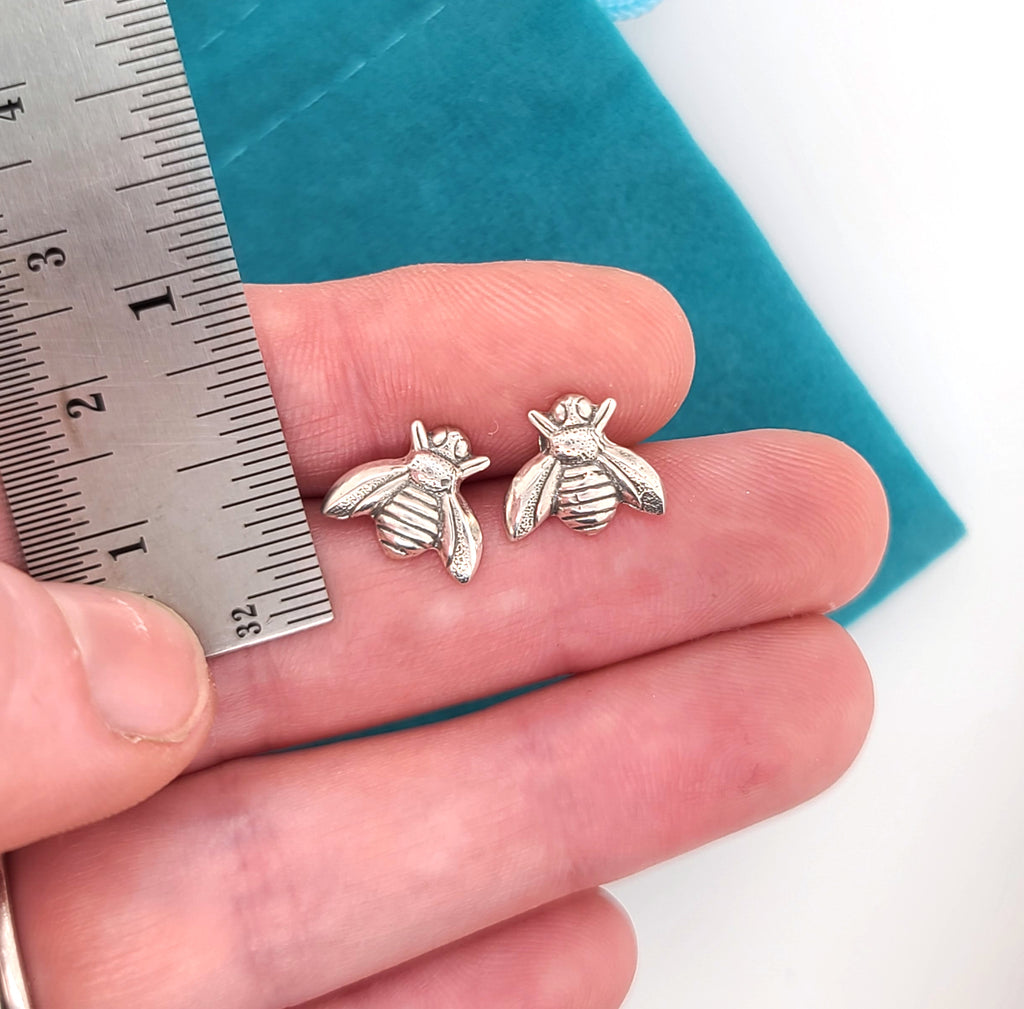 bee stud earrings by a ruler for scale