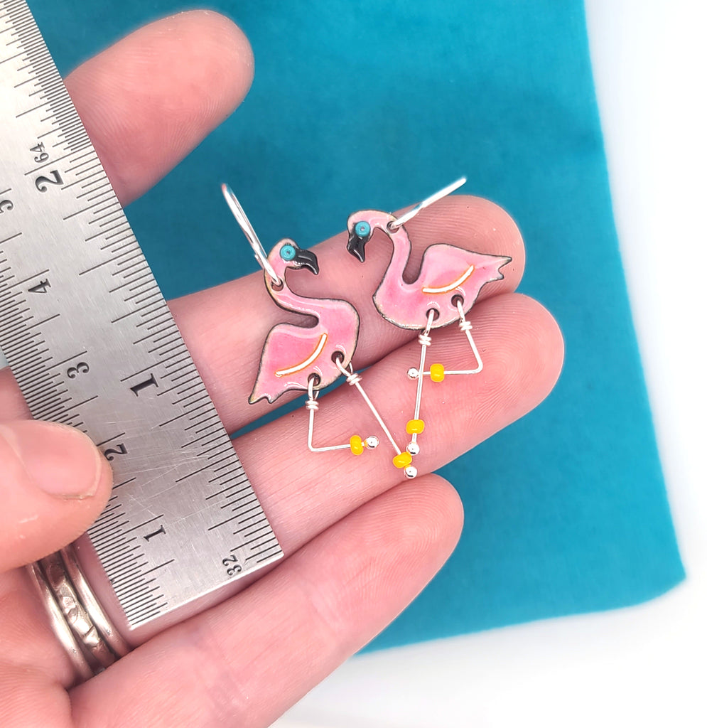handmade flamingo earrings next to ruler