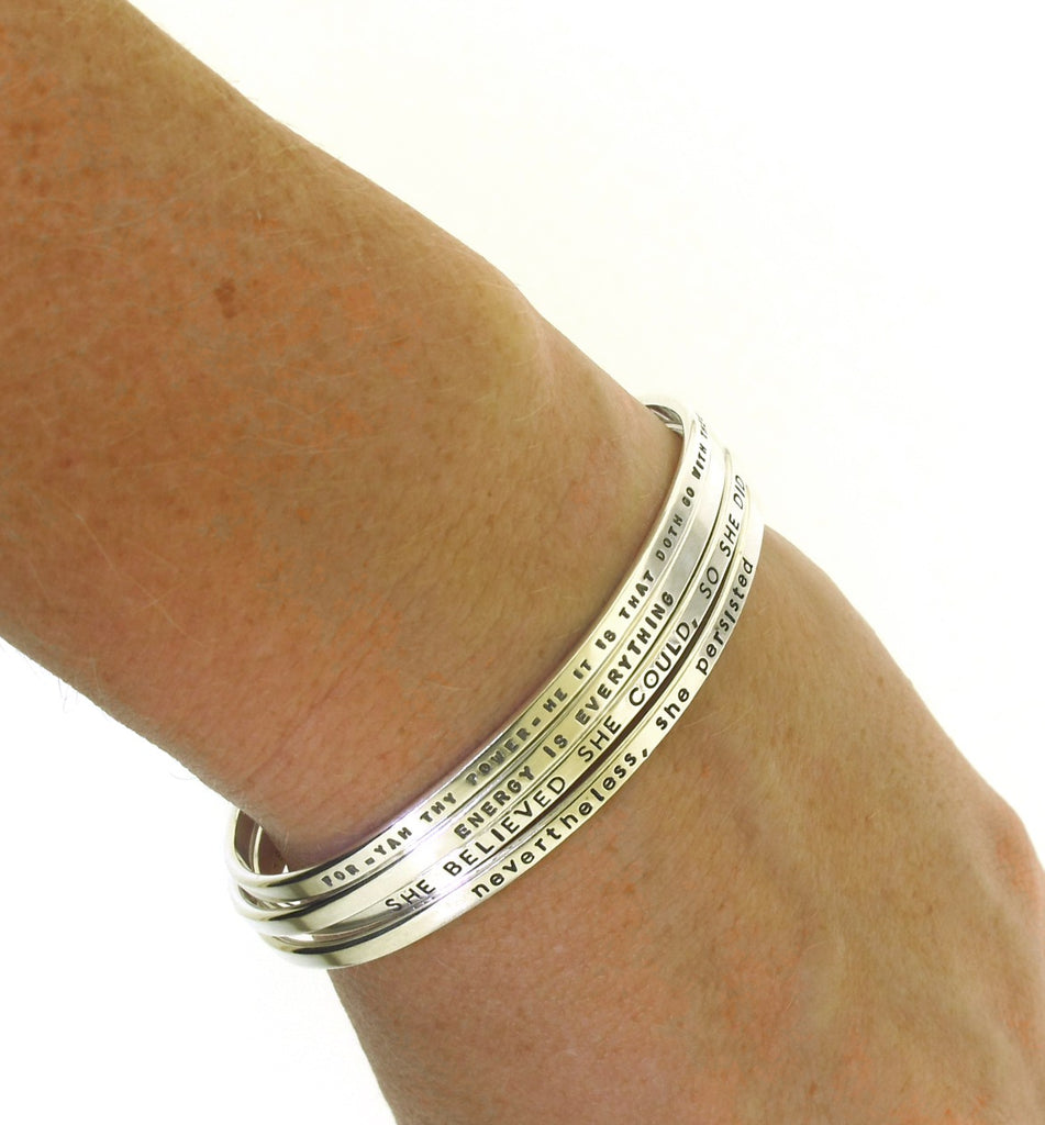 four handstamped silver cuff bracelets with inspirational messages made by kathryn riechert jewelry worn by model
