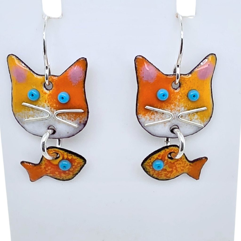 Cat-shaped earrings with fish dangles on a white background