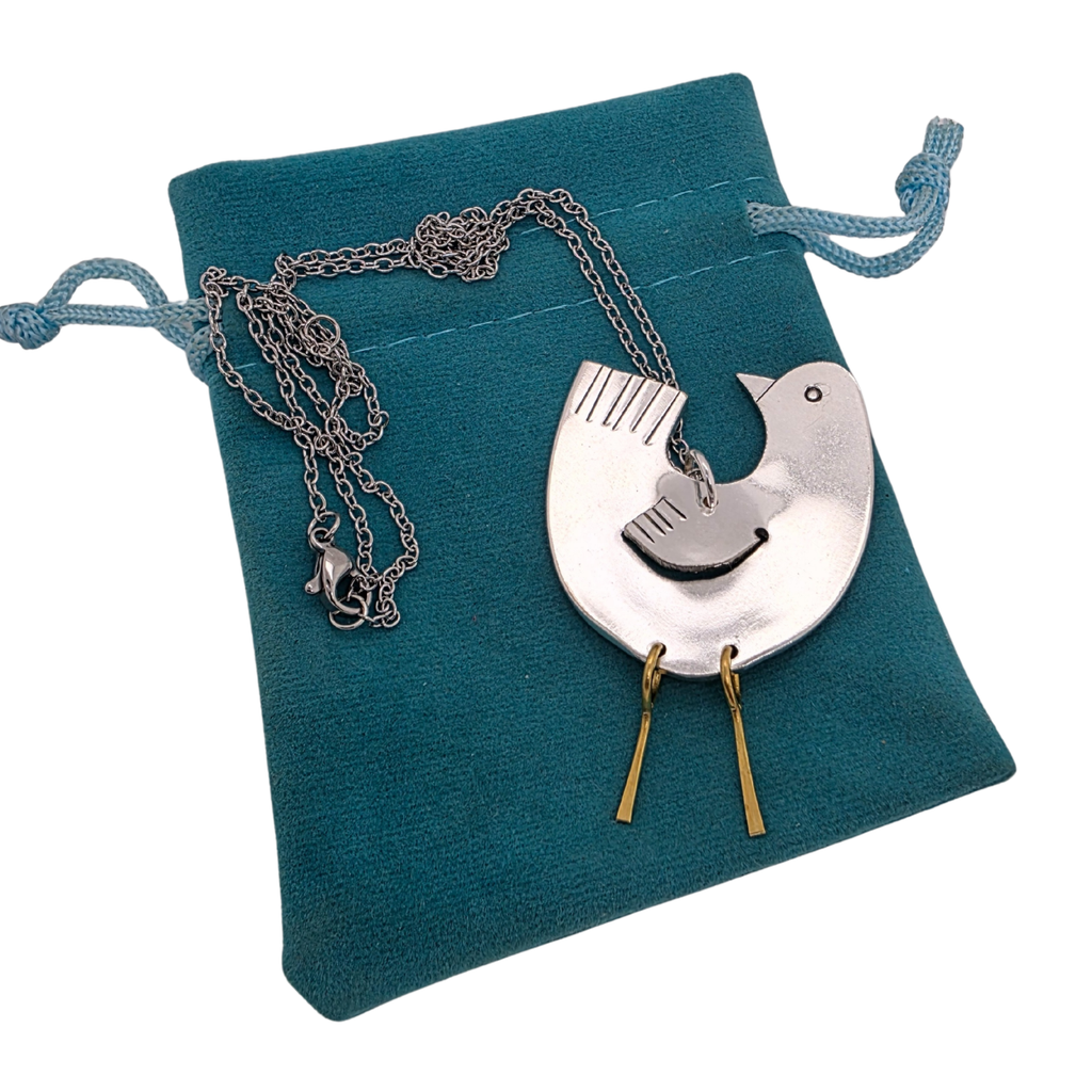 Silver necklace with a unique pendant on a teal jewelry pouch.