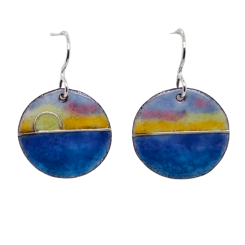 Round earrings with blue, yellow, and pink  sunrise over the ocean design on a white background