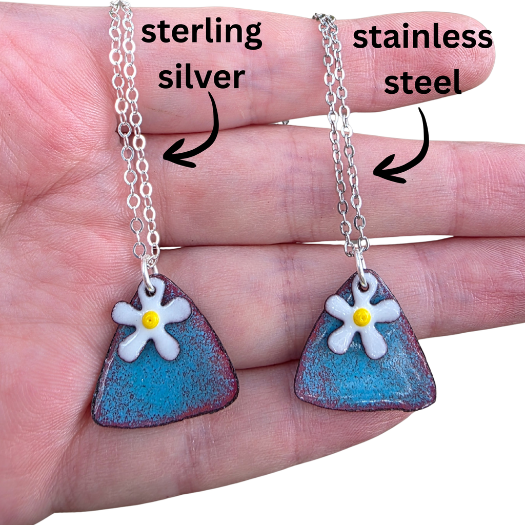 Two necklaces with floral pendants on a hand, labeled 'sterling silver' and 'stainless steel'.  Pendants are handmade from glass enamel fused to copper.