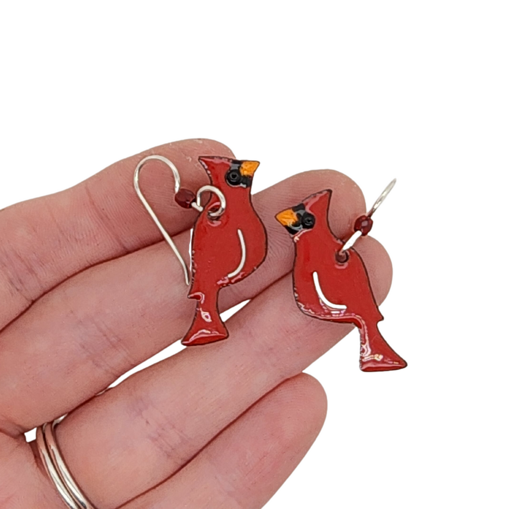 cardinal earrings in hand for scale