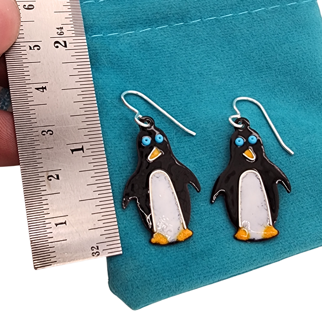 black and white penguin earrings next to ruler