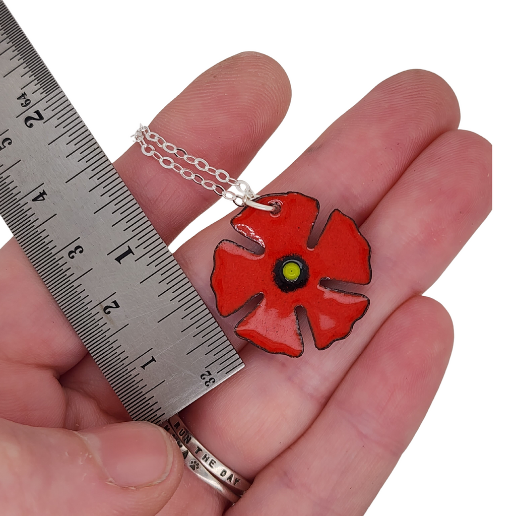 poppy pendant next to ruler for scale