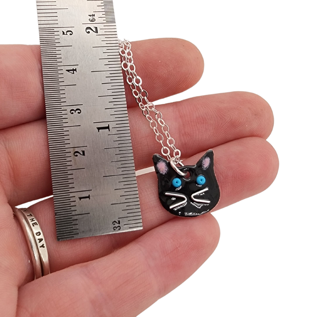 small cat head charm next to a ruler for scale