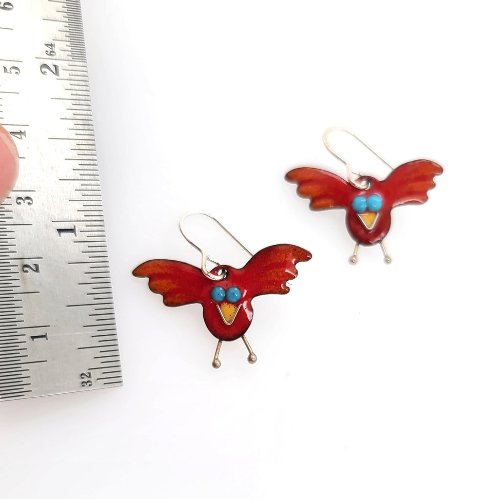 red bird earrings by a ruler