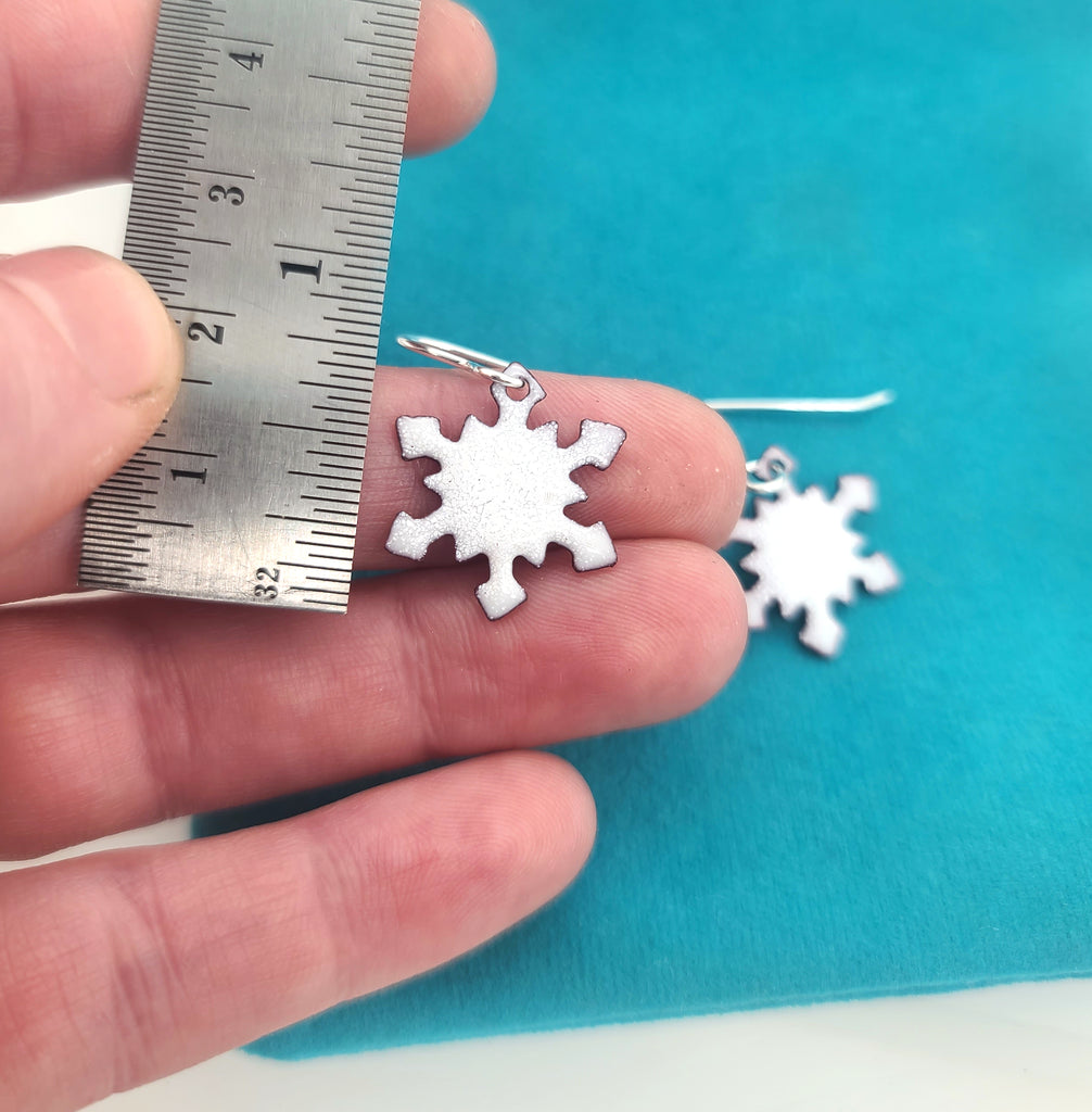 small snowflake earrings next to ruler