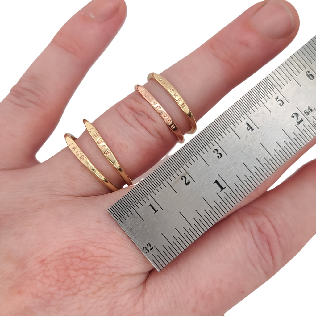 dainty gold stacking rings by ruler for scale